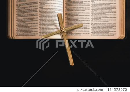 Palm leaf cross placed in open Bible with dark copy space, symbolizing Christian faith, Palm Sunday, Easter, worship and spiritual reflection, religion background for church, prayer, devotion concepts Palm leaf cross placed in open Bible with dark copy space, symbolizing Christian faith, Palm Sunday, Easter, worship and spiritual reflection, religion background for church, prayer, devotion concepts 134578970