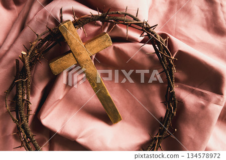 Wooden cross, crown of thorns on soft pink fabric, symbolizing Christian faith, sacrifice, crucifixion, Easter reflection, religious background, worship, prayer, spiritual devotion concepts Wooden cross, crown of thorns on soft pink fabric, symbolizing Christian faith, sacrifice, crucifixion, Easter reflection, religious background, worship, prayer, spiritual devotion concepts 134578972
