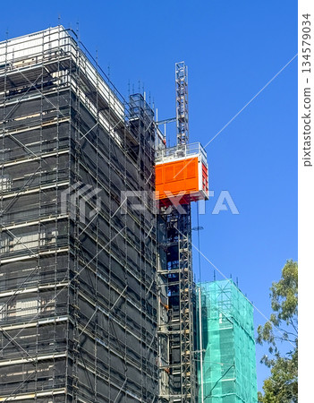 An industrial hoist operating on the side of a new building under construction An industrial hoist operating on the side of a new building under construction 134579034