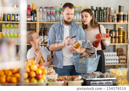 Family choose bottles of juice and scan QR code with smartphone in shop 134579510