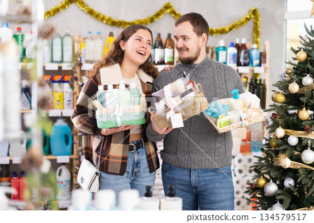 Couple choosing gift sets with self-care products in festive store Couple choosing gift sets with self-care products in festive store 134579517
