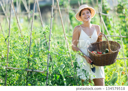 Young woman with basket in cottage garden Young woman with basket in cottage garden 134579518