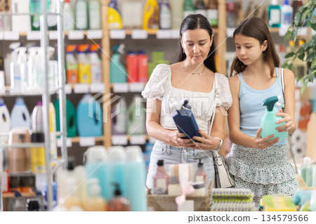 Woman with daughter choosing cleaning spray 134579566