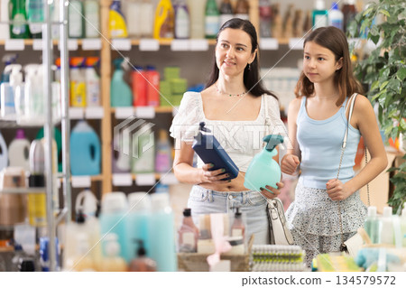 Woman with teen daughter choosing cleaning spray in store 134579572