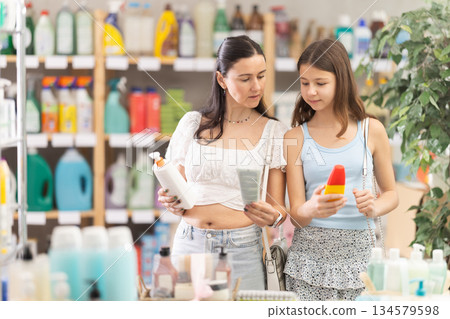Mother and daughter choosing sunscreen in supermarket 134579598