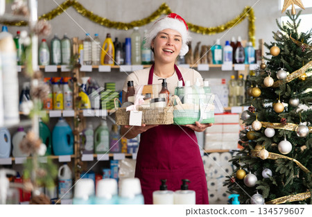 Woman seller in Santa hat presents festive set of shower cosmetics 134579607