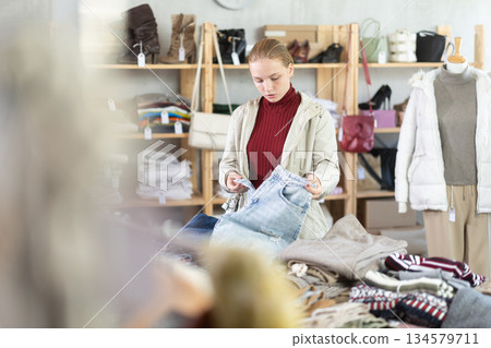 Selective teen girl choosing jean pantaloons in clothing store Selective teen girl choosing jean pantaloons in clothing store 134579711