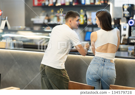 Couple man and woman drinking coffee and talking in cafe Couple man and woman drinking coffee and talking in cafe 134579728