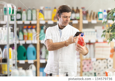 Man buyer scans qr code on sewer cleaner liquid label 134579736