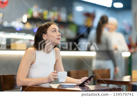 Young woman with phone in cafe Young woman with phone in cafe 134579741