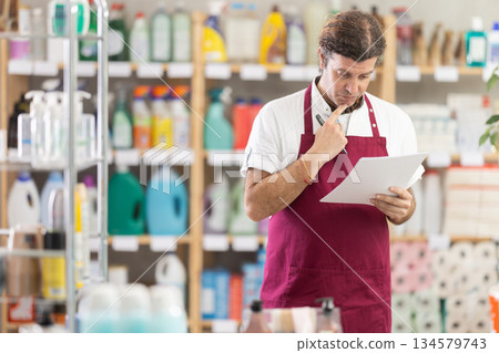 Anxious man seller with checklist in decorated store Anxious man seller with checklist in decorated store 134579743