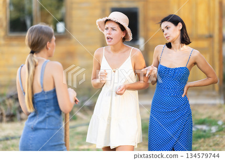 Three women arguing outside country house Three women arguing outside country house 134579744