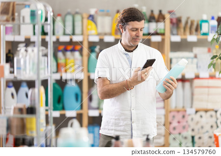 Man buyer scans qr code on shower gel label Man buyer scans qr code on shower gel label 134579760