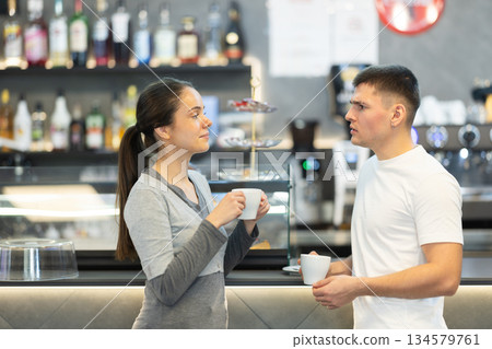 Young couple talking and drinking coffee in cafe Young couple talking and drinking coffee in cafe 134579761