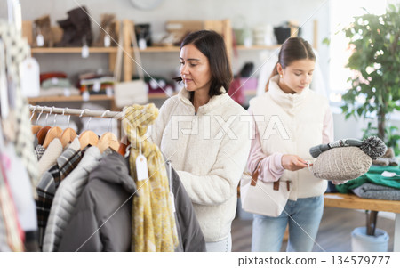 Adult woman and teenage girl choose hat 134579777