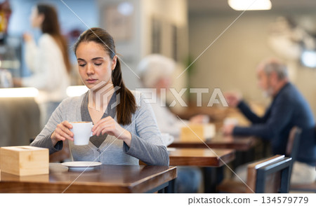 Pretty girl drinks coffee in cafe interior Pretty girl drinks coffee in cafe interior 134579779