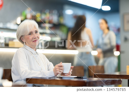 Eldery woman drinks coffee in cafe Eldery woman drinks coffee in cafe 134579785