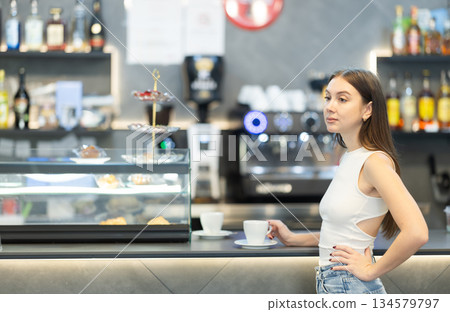 Young female cafe patron client drink coffee at bar counter 134579797