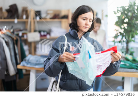 Woman looks at products in store and selects panties. Family shopping 134579836