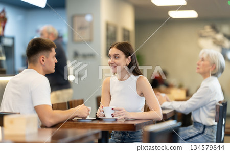 Young couple talking over a cup of coffee in a cozy cafe 134579844