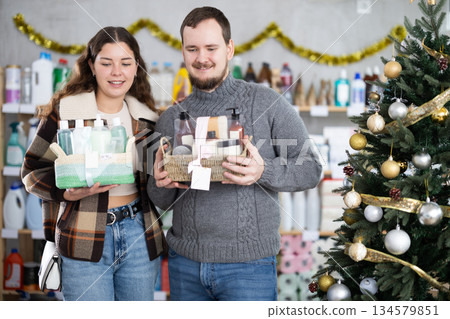 Positive family couple choosing gifts for New Year in household department of supermarket Positive family couple choosing gifts for New Year in household department of supermarket 134579851