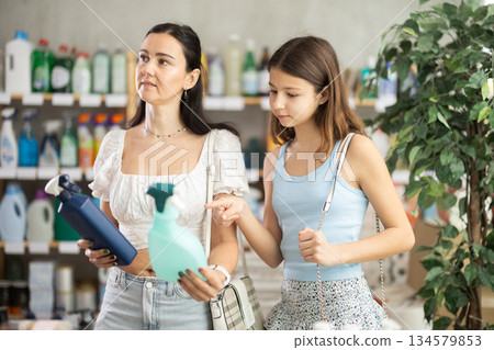 Woman with teen daughter choosing cleaning spray in store Woman with teen daughter choosing cleaning spray in store 134579853