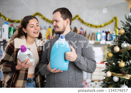 Happy man and woman looking for household liquid detergents on shelves in store. Christmas shopping 134579857
