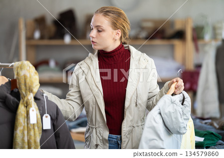 While shopping, teen girl browsing goods items and choose elect something warm outerwear in store 134579860