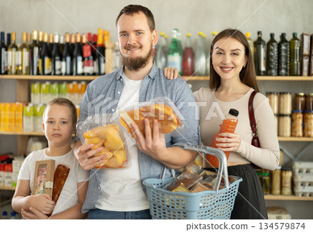 Family with various products in hands continuing shopping in grocery department of supermarket 134579874
