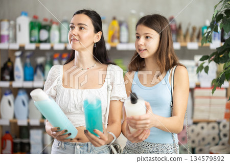 Woman with daughter choosing shampoo or shower gel 134579892