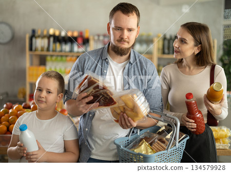 Couple of man and woman with boy choosing food in grocery Couple of man and woman with boy choosing food in grocery 134579928