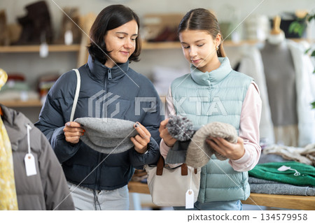 Adult woman and teenage girl choose hat 134579958