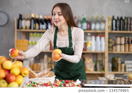 Young woman seller puts apples on counter 134579965
