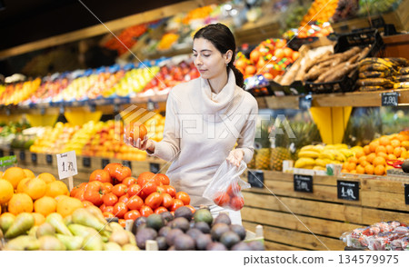 Young woman choosing tomatos in vegetable shop 134579975