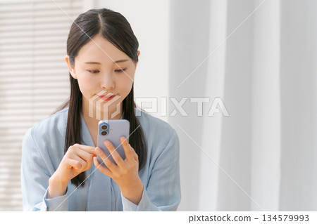 A young woman operating a smartphone A young woman operating a smartphone 134579993