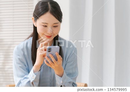 一個操作智能手機的年輕女子 134579995