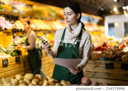 Upset woman owner of greengrocer with paper document and phone Upset woman owner of greengrocer with paper document and phone 134579996