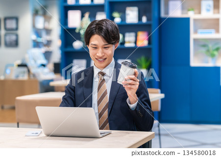 工作在辦公室的一個年輕商人 工作在辦公室的一個年輕商人 134580018