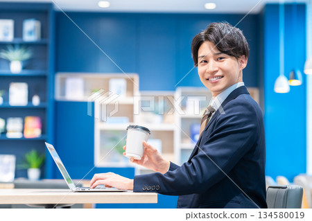 工作在辦公室的一個年輕商人 工作在辦公室的一個年輕商人 134580019