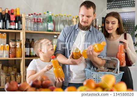 Preteen boy with mom and dad choosing juices in supermarket Preteen boy with mom and dad choosing juices in supermarket 134580020