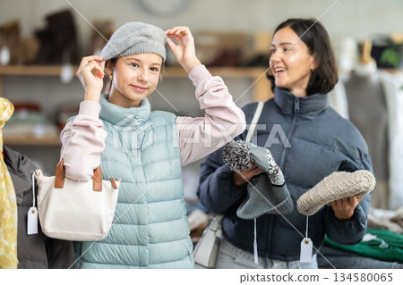 Adolescence girl try on hat during shopping with mother in clothes store, family shopping with mom Adolescence girl try on hat during shopping with mother in clothes store, family shopping with mom 134580065