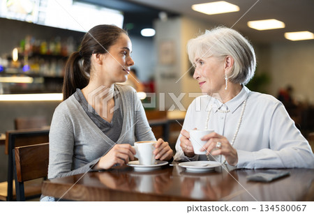Young woman chatting with elderly woman in cafe Young woman chatting with elderly woman in cafe 134580067