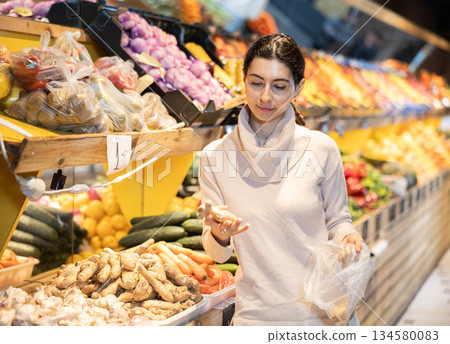 Young woman choosing ginger in vegetable shop 134580083