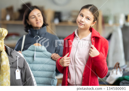 Teenage girl with her mother try on coat in store 134580091