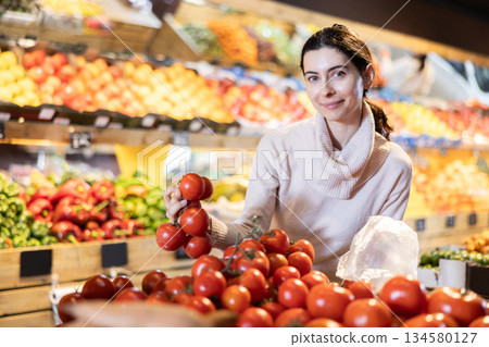 In vegetable store, young woman customer buy tomato In vegetable store, young woman customer buy tomato 134580127