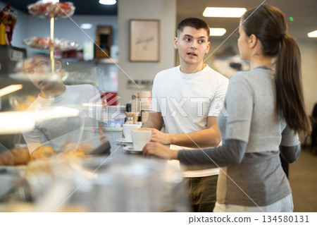 Couple man and woman drinking coffee and talking in cafe 134580131