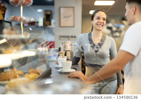guy and a young woman are standing at the counter in a cafe guy and a young woman are standing at the counter in a cafe 134580136