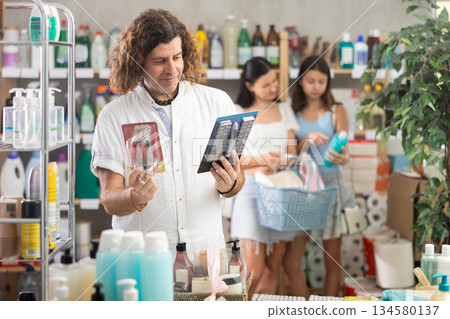 Man choosing razor while mom and daughter doing shopping in background Man choosing razor while mom and daughter doing shopping in background 134580137