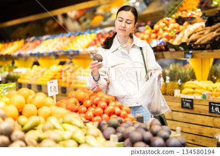 Woman shopping in grocery supermarket - choosing ripe passion fruit 134580194