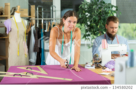 Female designer cutting fabric for custom garment in sewing sewing Female designer cutting fabric for custom garment in sewing sewing 134580202